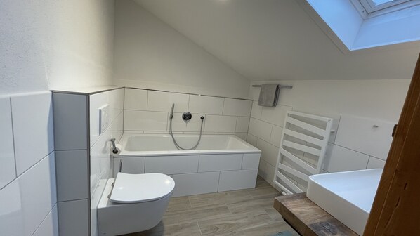 A compact bathroom with a shower, toilet, and bathtub.