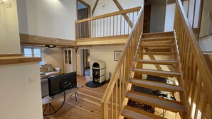 A spacious loft with a wooden staircase, a fireplace, and a cozy seating area. - Unique, quiet vacation apartment on two floors for 4 people (Marquartstein)