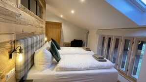 A bedroom with two beds, wooden paneling, a skylight, and a view of the outdoors. - Unique, quiet vacation apartment on two floors for 4 people (Marquartstein)