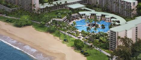 An aerial view of a resort with a large pool area, multiple buildings, and a beach.