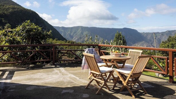 Une terrasse avec une table et des chaises, donnant sur un paysage montagneux.