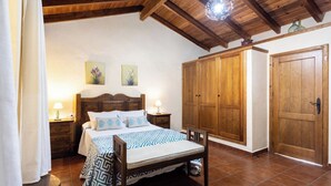 Une chambre à coucher avec un lit en bois, deux tables de chevet, une armoire et une porte.