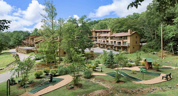 A resort with multiple-story buildings, a golf course, and a well-maintained landscape.