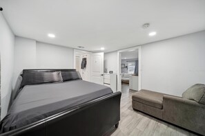 A modern bedroom with a large bed, a small sofa, and a walk-in closet.