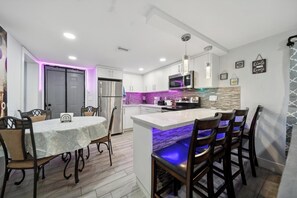 A modern kitchen with white cabinets, a central island with bar seating, a built-in microwave, and pendant lighting.