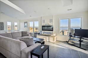 Relax in this stylish living room with a large window overlooking the beach, flat-screen TV, and comfortable sofa.