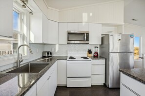 Enjoy cooking in this well-lit kitchen with a gas stove, microwave, and stainless steel sink.