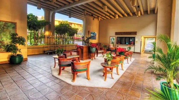A spacious lobby with a tiled floor, wooden chairs, and potted plants. - Oceanfront Condo/Hawaiian Style. 1Bd, w/AC & Wifi (Kailua-Kona)