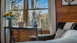 A cozy room with a wooden table, a vase with yellow flowers, a candle, and a framed deer head on the wall. - Private Hiking Trail, Full Game Rm, Great Location (Morganton)
