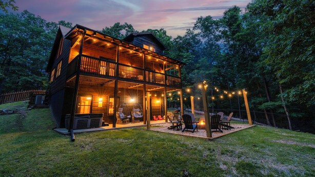 A two-story wooden cabin with a balcony, string lights, and outdoor seating. - Private Hiking Trail, Full Game Rm, Great Location (Morganton)