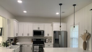 A modern kitchen with white cabinets, stainless steel appliances, and a central island.