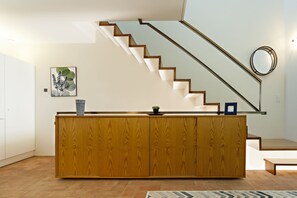 A modern kitchen with a wooden island, a staircase, and a wall-mounted mirror.