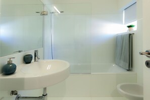 A modern bathroom with a white sink, a glass shower enclosure, and a bathtub. - Historic & Emblematic - Convent of Bernardas (Tavira)