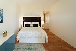 A bedroom with a bed, bedside tables, a nightstand, a rug, and a painting on the wall. - Historic & Emblematic - Convent of Bernardas (Tavira)