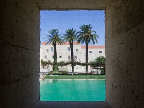 A view through a window of a pool area with a building in the background.