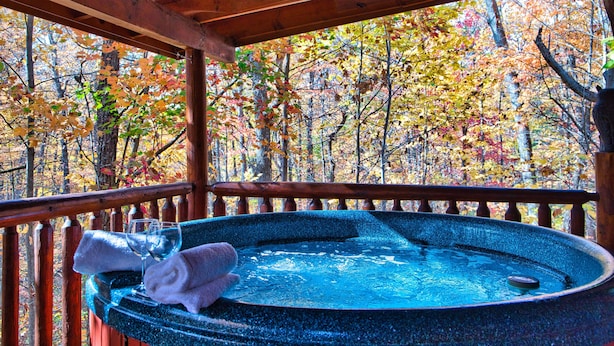 Une terrasse en bois avec un jacuzzi, un verre et une serviette.