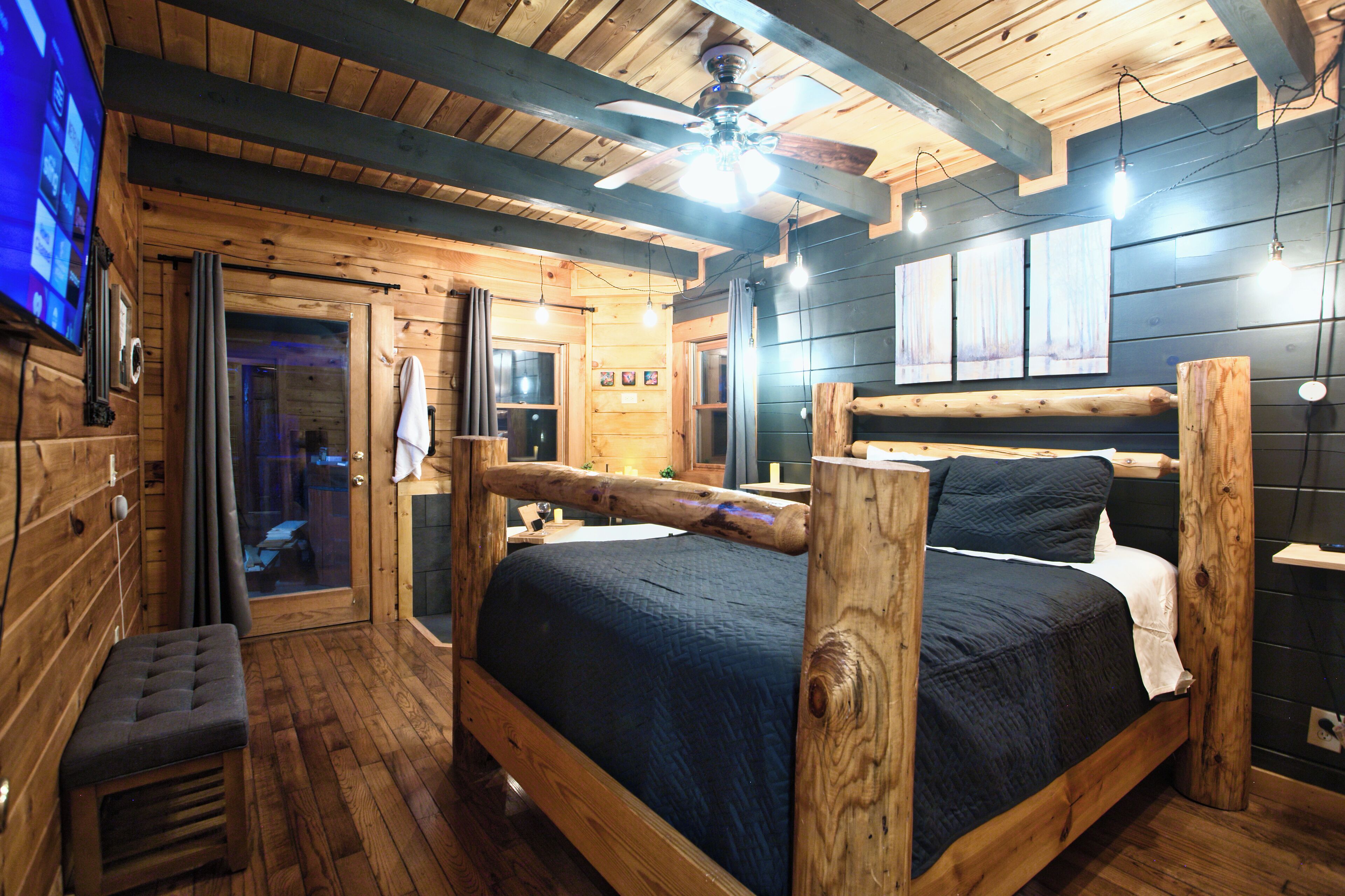 A wooden cabin-style room with a bed, a bench, and a ceiling fan.