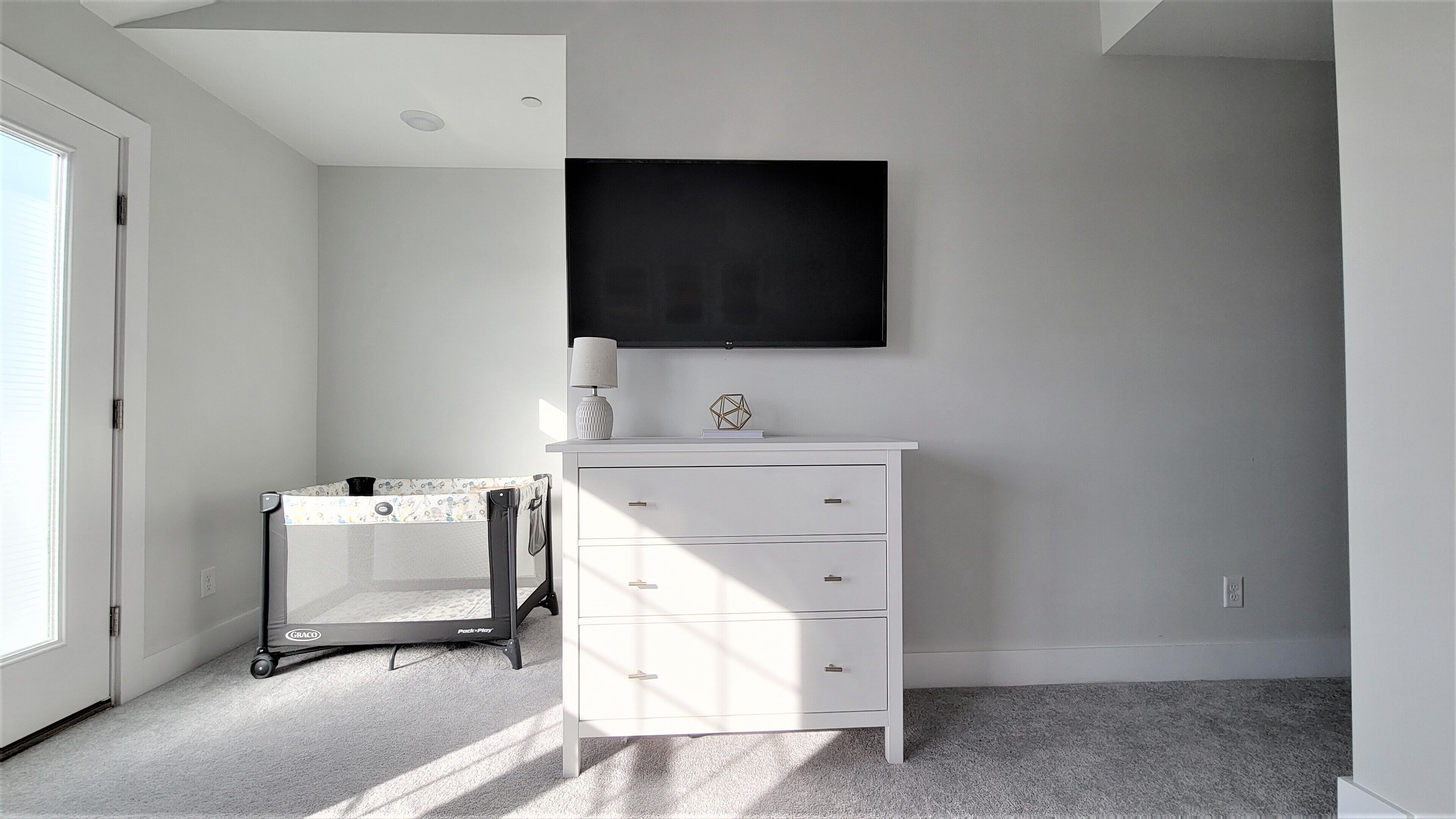 Una habitación con un aparador blanco, una mesita con una lámpara y una obra de arte negra grande en la pared.