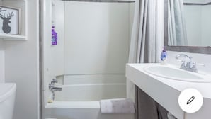 A bathroom with a white sink, a mirror, a shower curtain, and a framed picture on the wall. - Ski In Ski out Cozy Condo in Creekside forest (Whistler)