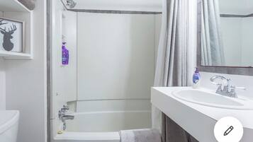 Tina con regadera, toallas, jabón, shampoo