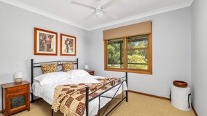 A bedroom with a bed, a nightstand, a window, and two framed pictures on the wall.