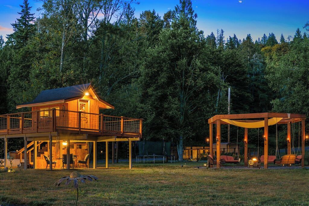 A wooden cabin with a balcony and a covered outdoor seating area.