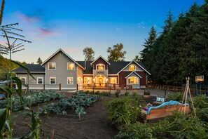 Een groot huis met een verzorgde tuin en een basketbalveld.