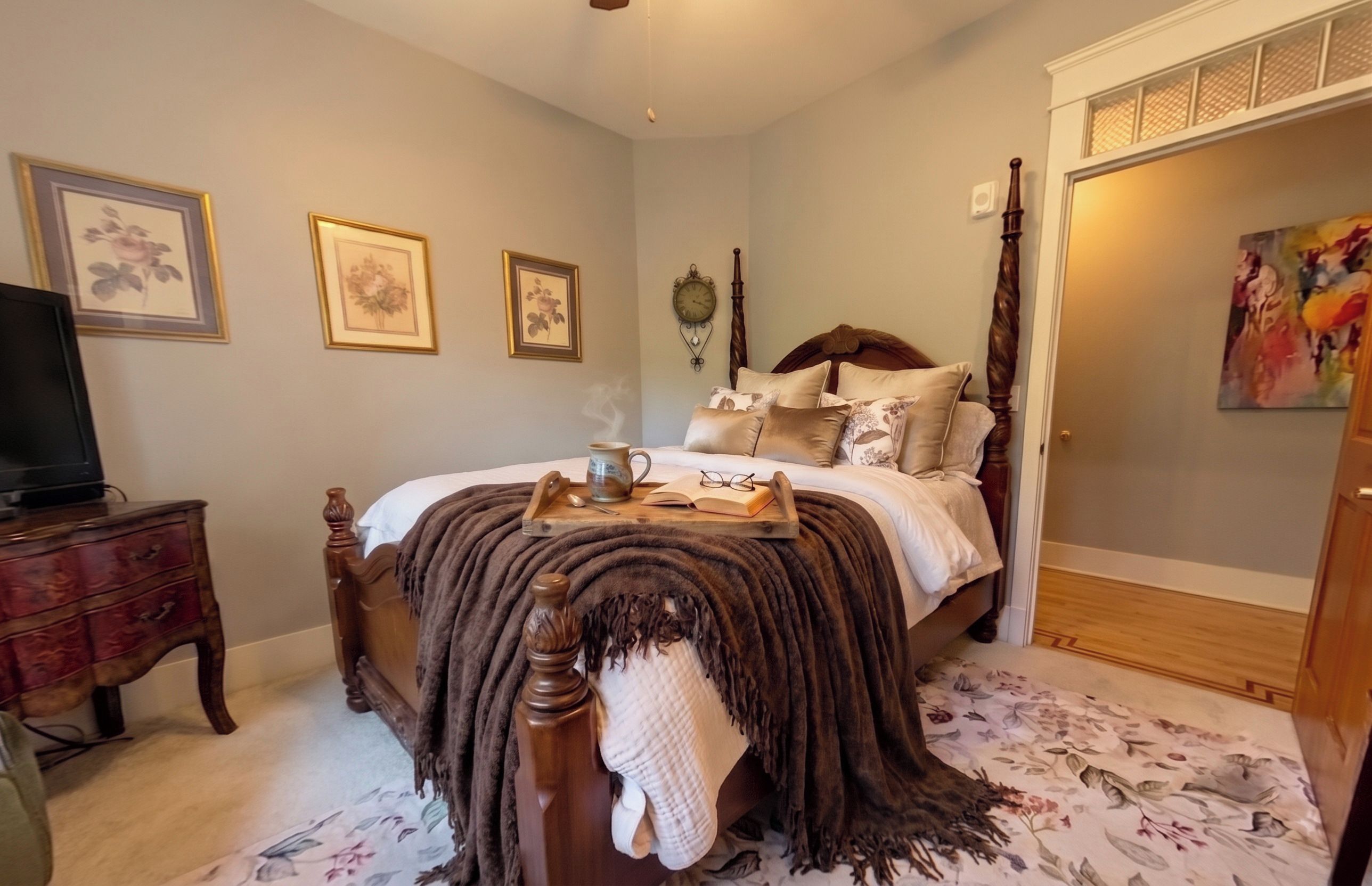 A bedroom with a bed, a dresser, a television, and a painting on the wall.