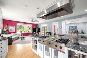 A spacious kitchen with a large island, modern appliances, and a bright, airy room with red walls and large windows. - Grayson B&B — ADA Garden View Suite — Minutes to Evergreen Fairgrounds (Monroe)