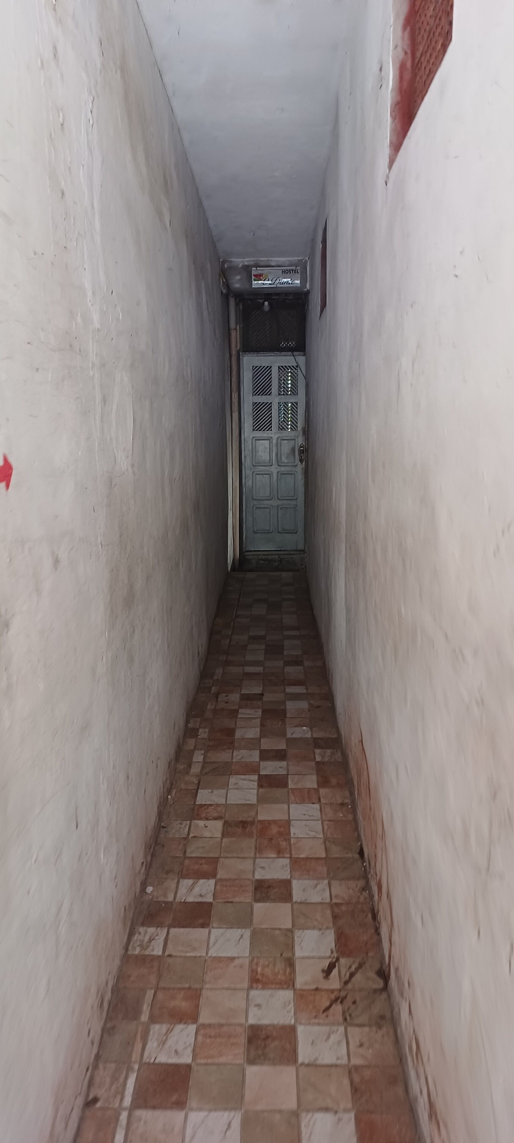 A narrow hallway with checkered tiles and a door at the end.