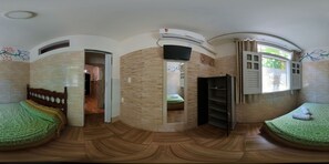 A room with a curved ceiling, a bed with a green patterned bedspread, a wooden floor, a built-in shelf, and a window with curtains. - Apartment Perto da Primeira Praia (Cairu)