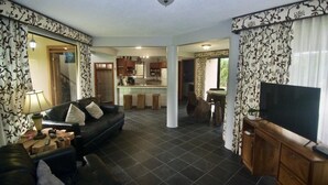Una sala de estar con sofá, televisor y un comedor con mesa y sillas.