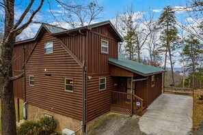 Une cabane en bois brun avec un porche et une allée en béton.