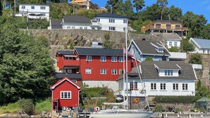 A coastal village with houses on a hillside, a dock with a boat, and a lighthouse. - Stunning apartment in Arendal with WiFi (Arendal)