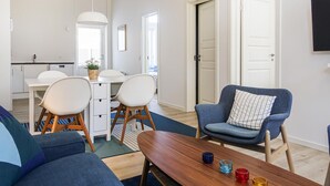 Un espace de vie moderne comprenant un coin repas, un canapé, un fauteuil bleu et une table en bois décorée de bougies.