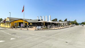 Un bâtiment jaune avec une enseigne indiquant « GALERIE » et un mât sur lequel flotte un drapeau.
