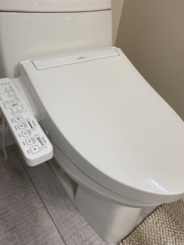 Des toilettes dotées d’une télécommande située sur le côté gauche.