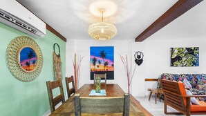 Een eetgedeelte met een houten tafel, stoelen, een hanglamp en wanddecoratie.