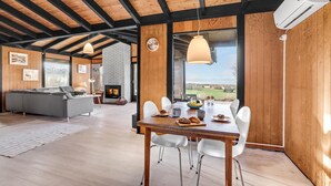 A modern interior with a dining area, a fireplace, and a view of the outdoors.