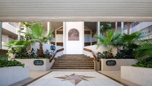 A hotel lobby with a central staircase, palm plants, and a star-shaped floor design. - Sandcastle Court #277 -Kitchen (Fernandina Beach)
