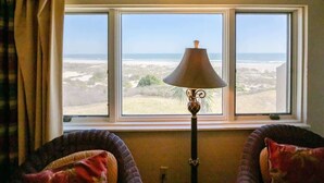 A room with a large window overlooking a beach, a lamp, and two chairs. - Sandcastle Court #277 -Kitchen (Fernandina Beach)