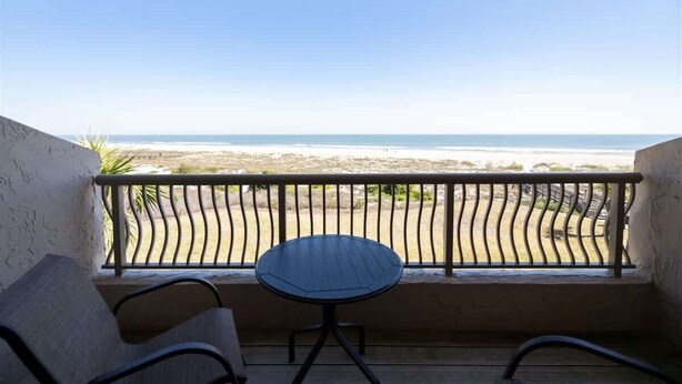 A balcony with a view of the beach, a round table, and two chairs. - Sandcastle Court #277 -Kitchen (Fernandina Beach)