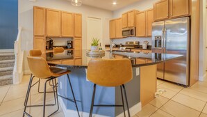 Una cucina moderna con mobili in legno, elettrodomestici in acciaio inossidabile e un'isola centrale con sgabelli da bar.
