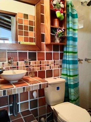 Et badeværelse med flisebeklædt backsplash, en vask, et toilet og en badeforhæng.