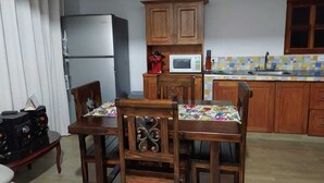 A kitchen with wooden cabinets, a refrigerator, a microwave, and a dining table with chairs. - Samaria, a place to rest and enjoy in Santa Elena (Santa Elena)