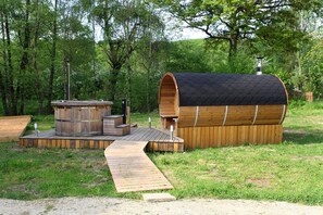 Een houten chalet met een groot, trommelvormig dak, een jacuzzi en een houten terras.