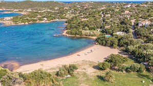 An aerial view of a coastal area with a beach, clear blue waters, and surrounding greenery. - Beautiful apartment in Porto Cervo (Porto Cervo)