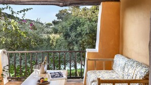 A balcony with a wooden table, a sofa, and a bottle of champagne. - Beautiful apartment in Porto Cervo (Porto Cervo)