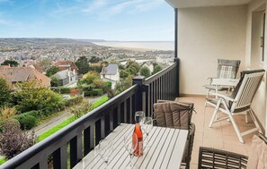 En balkon med bord og stole, der kigger ud over en kystby.