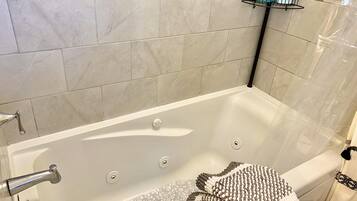 Une salle de bain avec une baignoire, un porte-serviettes avec des articles de toilette et un mur carrelé.